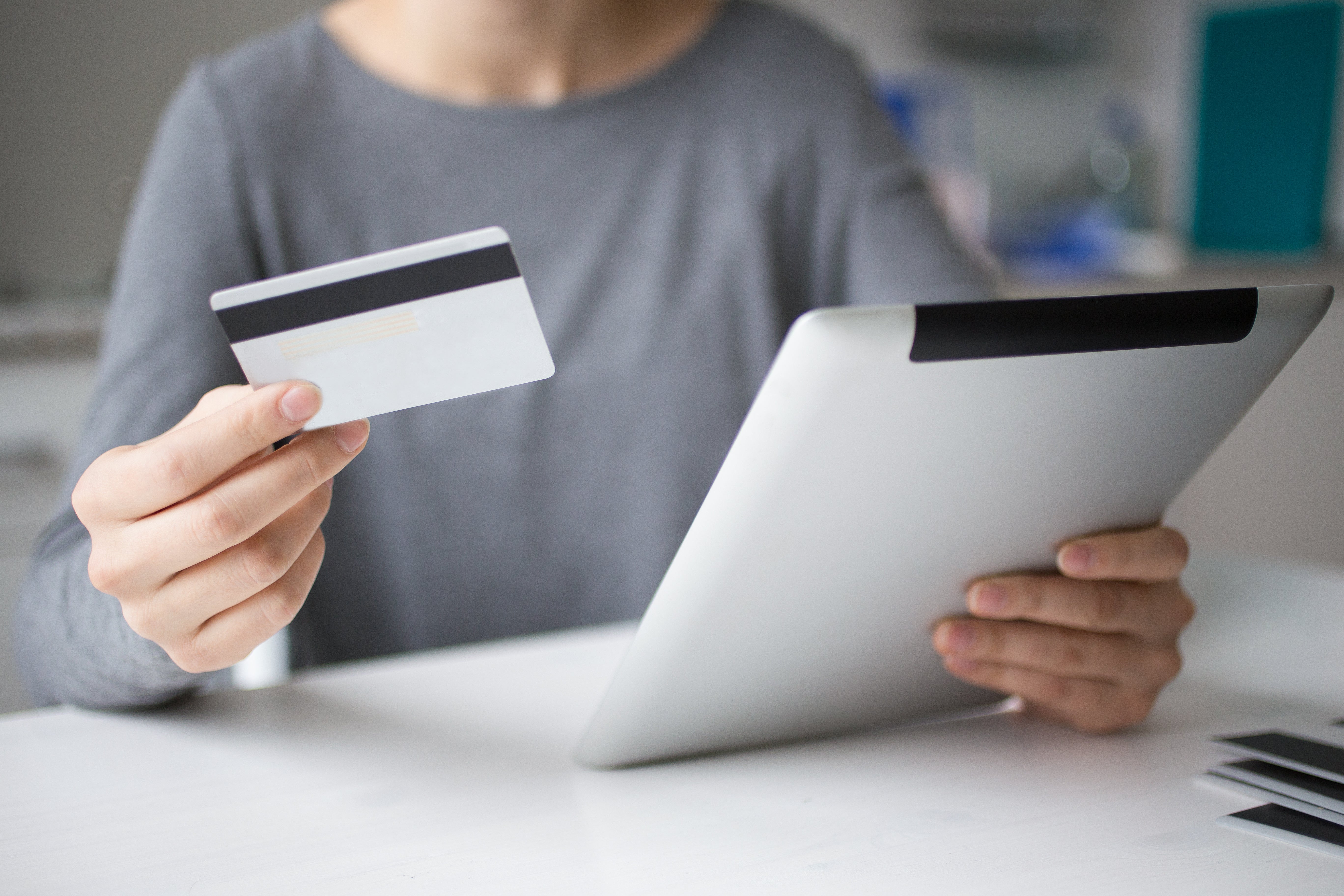 A woman holds a tablet showing an invoice. She also holds a credit card, representing that her business had ordered eSIMs.